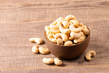 Organic roasted cashew nuts in a wooden bowl. Top view. 