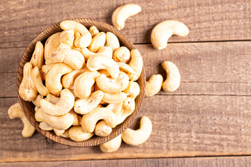Fototapeta premium Organic roasted cashew nuts in a wooden bowl. Top view. 