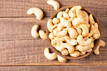 Organic roasted cashew nuts in a wooden bowl. Top view. 