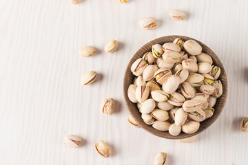 Organic roasted pistachio nuts in a wooden bowl. Top view. 