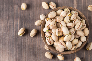 Organic roasted pistachio nuts in a wooden bowl. Top view. 