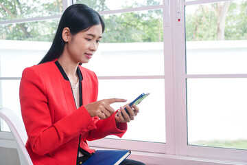 Asian businesswoman working in a modern office, focused on a task at hand. Amidst technology and paperwork, she exudes confidence, professionalism, and commitment in a corporate environment.