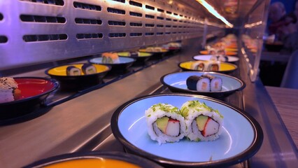 Colorful plates with fresh maki and nigiri transported on a Running sushi bar belt © 4kclips