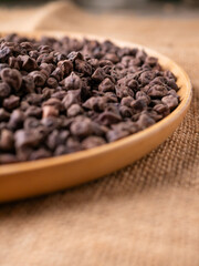 Raw Dark Brown Chickpeas (Kala Chana) on a rustic wooden table. Dry Balck chickpea (ceci neri) background close up.