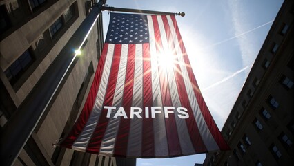Reciprocal tariffs bring a recession. American flag with "TARIFFS" displayed prominently under sunlight in an urban setting.