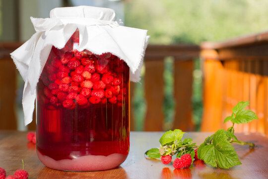A jar full of raspberries under a white cover