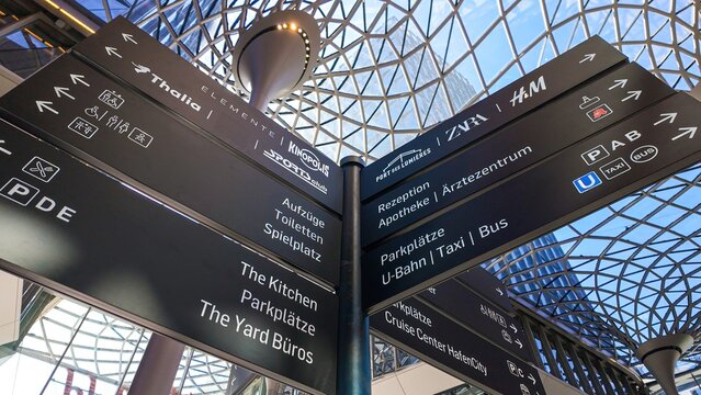 HAMBURG, GERMANY - APRIL 29, 2025 - Clear directional signs pointing towards various amenities and stores within Westfield Hamburg Uberseequartier, enhancing navigation for visitors