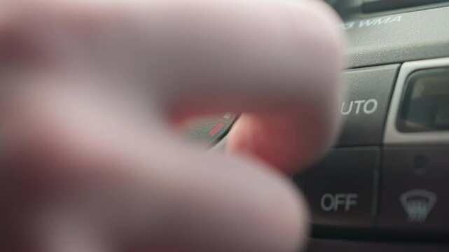 close up finger pressing off button on car air conditioning control panel with illuminated icons showing recirculation and defrost for authentic cabin interior detail softly under ambient light