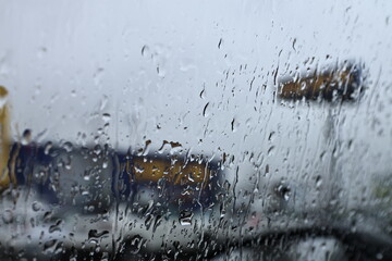 Raindrops on a car windshield during a rainy day. Blurred view through the glass captures the mood...