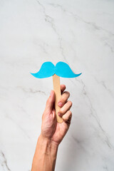 Male Hand holding blue mustache supporting prostate cancer awareness month and men's health