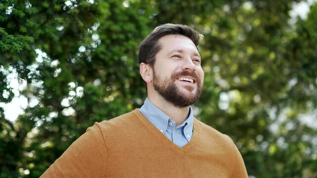 Happy businessman relaxing with closed eyes standing in urban city park. A smiling handsome bearded male in glasses feels relief and peace, breathes deeply, savoring fresh air, enjoys being in nature