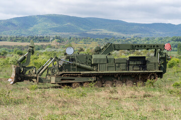 Green military engineering vehicle with crane and bulldozer blade