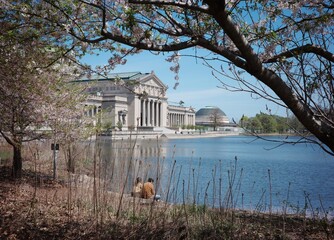 A couple sit in front of a pond in a beautiful day in Jackson Park in Chicago
