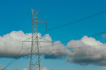Steel lattice transmission towers supporting high voltage power lines under a bright blue sky with...