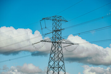 Steel lattice transmission towers supporting high voltage power lines under a bright blue sky with...