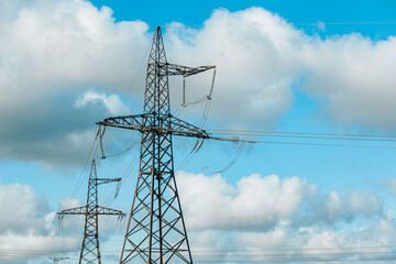 Steel lattice transmission towers supporting high voltage power lines under a bright blue sky with...