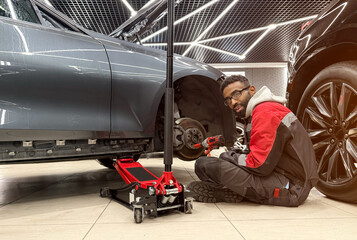 An African-American tire fitter with a wrench in his hands while working. The tire fitter removes...