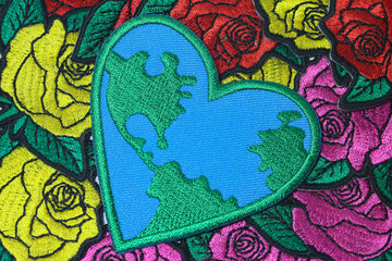 Central heart shaped Earth crafted from thread lying on lush floral background  illustrating the concept of love , planet care and natural beauty.