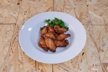 A plate of fried chicken with parsley on top. The chicken is cut into pieces and is served in a white bowl