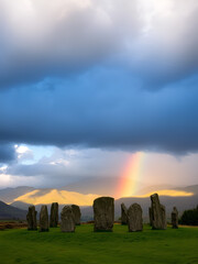 Rainbow over Castlerigg Stone Circle on summer solstice eve with sun and dark clouds over Cumbrian Mountains in Lake District Keswick England