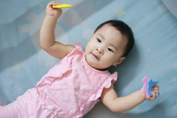 Child playing with colorful shapes on a soft mat in a cozy indoor space during daylight, showing...