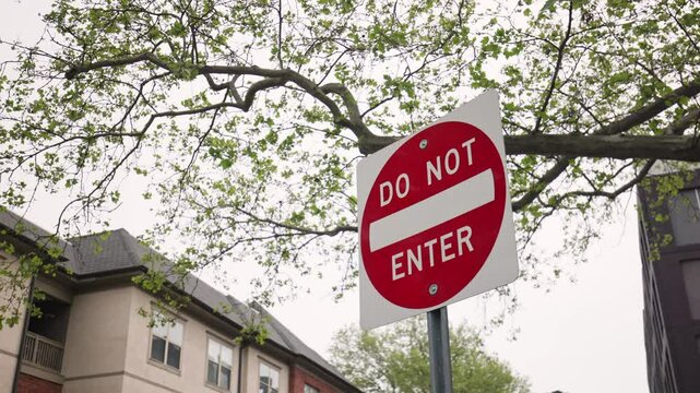 Red and white do not enter traffic and pedestrian sign signaling a blocked and closed route down a path and road roadway, blocking people, cars, and vehicles from entering due to closure in area
