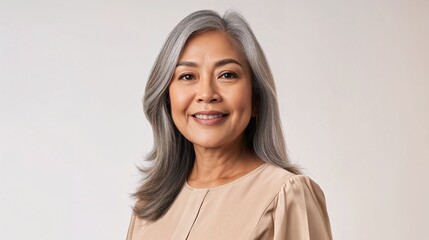 Portrait of smiling mature Filipino woman with gray hair on light background