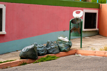 garbage bags and a rusty dumpster in the colorful streets of la paz bolivia,latinoamerica - garbage...