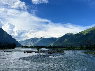 Serene mountain landscape with river flowing through green valley under blue sky