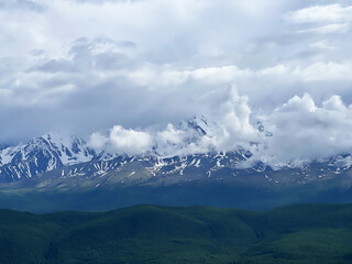 Fototapeta premium Majestic snow-capped mountains and rolling hills under cloudy sky