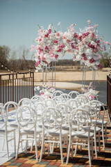 Rectangular arch for a wedding ceremony by the river. White chairs for guests. Outdoor ceremony