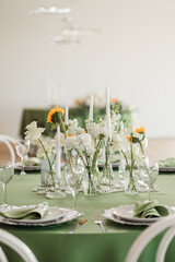Wedding banquet hall decor with round green tables, white roses and sunflowers on the tables