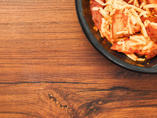 Ready made dish with wedges, garlic sauce and cheese in plastic tray on wooden table surface. Fast food made of high quality products ingredients. Lunch for cooking in microwave. Copy paste space.