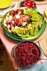 Beet root salad with horse radish in a bowl on a festive table with a plate with meat appetizers