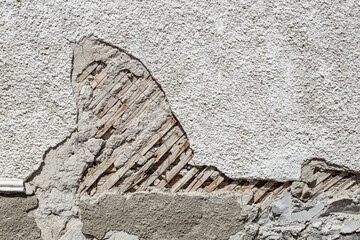 Damaged wooden house wall with wood grid and crumpling concrete stucco, abstract obsolete textured...