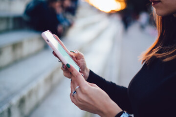 Crop woman using smartphone on street