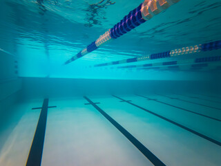 Underwater view of a deep swimming pool with a noticeable change in depth, clear water, and lane markers. Ideal for illustrating sports, swimming lessons, or pool architecture.