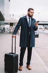 Confident businessman with luggage against airport