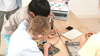 Group of diverse student working together on main board with laptop screen display engineering...