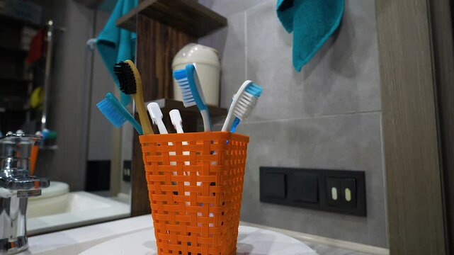 Toothbrushes in a glass case in the bathroom, multi-colored toothbrushes spinning on the table. Slow motion.