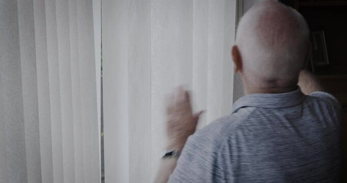 Senior man, window and waving hand while opening blinds to greet a neighbor or person with hello in morning during retirement. Elderly man in his Uk house to doing wave for kindness or goodbye