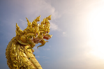 Golden Naga Statue with Three Heads under Morning Sunlight and Clear Sky