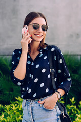 Fototapeta premium Cheerful woman speaking on smartphone on street
