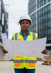 Black female engineer reviewing blurred blueprint on site
