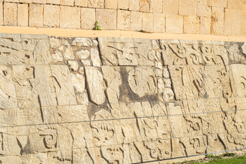 Ancient Mayan stone wall carvings in Mexico. Historical relief depicting figures and symbols, showcasing rich cultural heritage under natural sunlight.
