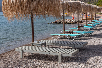 Sun beds under a straw umbrella by the sea. A tropical beach. Summer outdoor recreation. Blue...