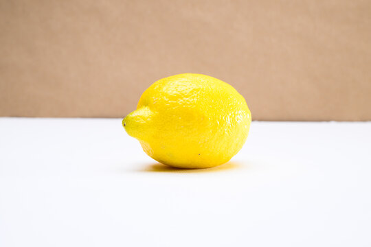 A lemon on a white tabletop against a brown background