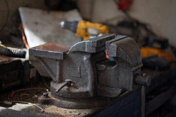 Old metal bench vise mounted on a workbench in a workshop