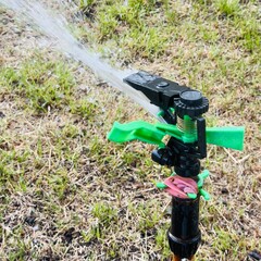 watering the lawn in the garden with a sprinkler