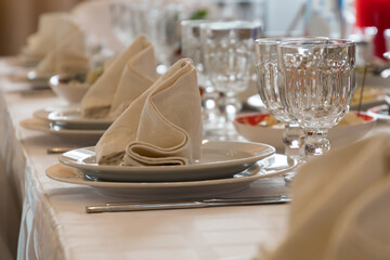 Table setting with dishes and napkins, festive food in the restaurant. Dinnerware on a luxurious table. Reception of guests, service for the rich.